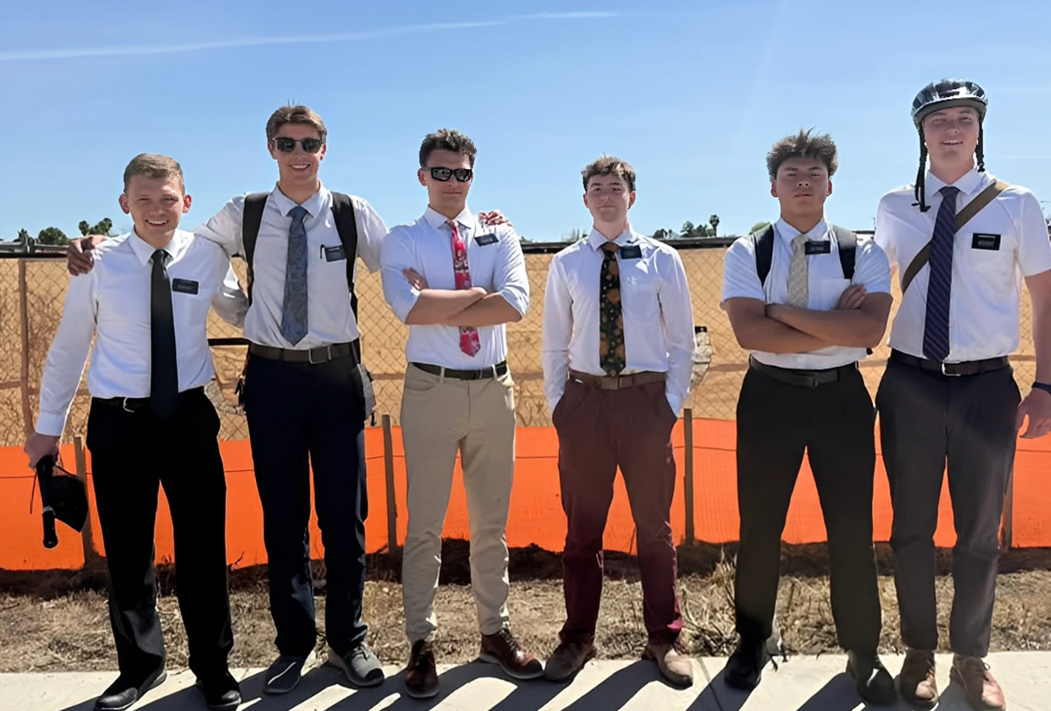 Six men standing outdoors, wearing formal attire.