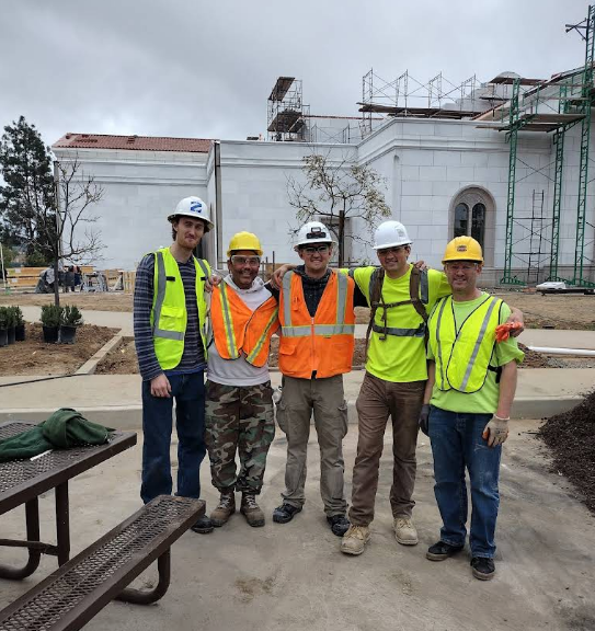Five workers in hard hats at construction site